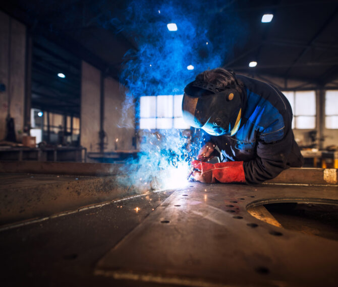 Close up view of worker welding metal construction in industrial workshop.